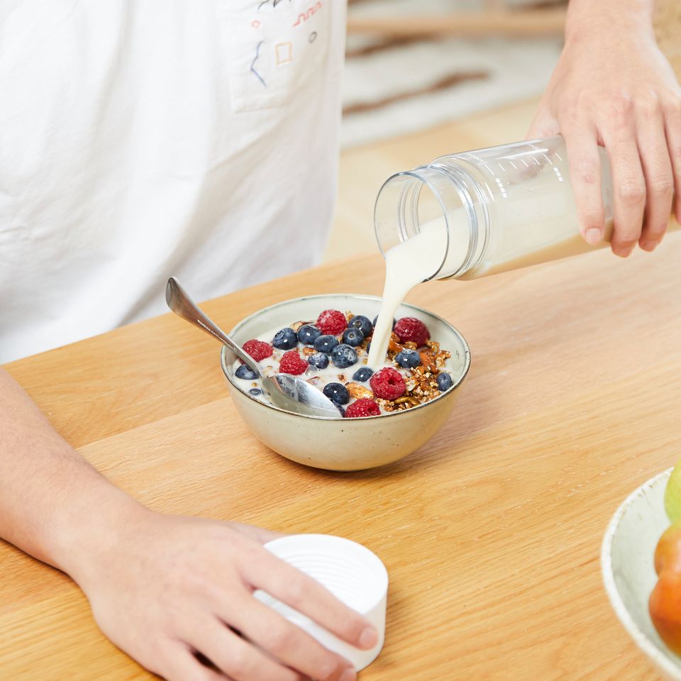 Nimbus oat milk poured over a bowl of granola and berries